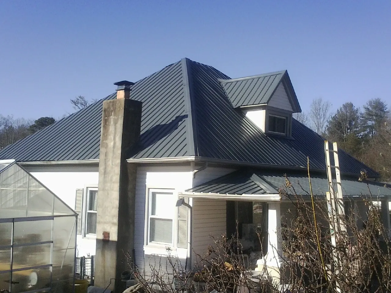 Dark blue standing seam metal roof on a white farmhouse with dormer — Slate & Tile Roof Repair by Roofing Brothers in Sebeka