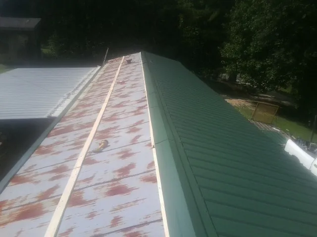 Old rusted panels beside newly installed green metal roofing — Wind Damage Roof Repair by Roofing Brothers in Sebeka