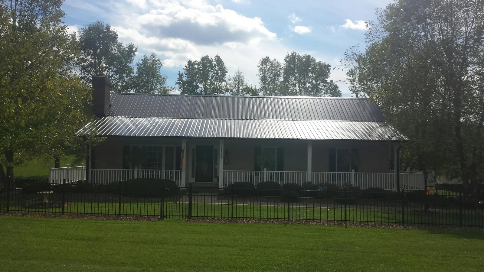 Gray metal roof on a brick ranch with a full width front porch — Gutter Guard Installation work by our crew in Sebeka