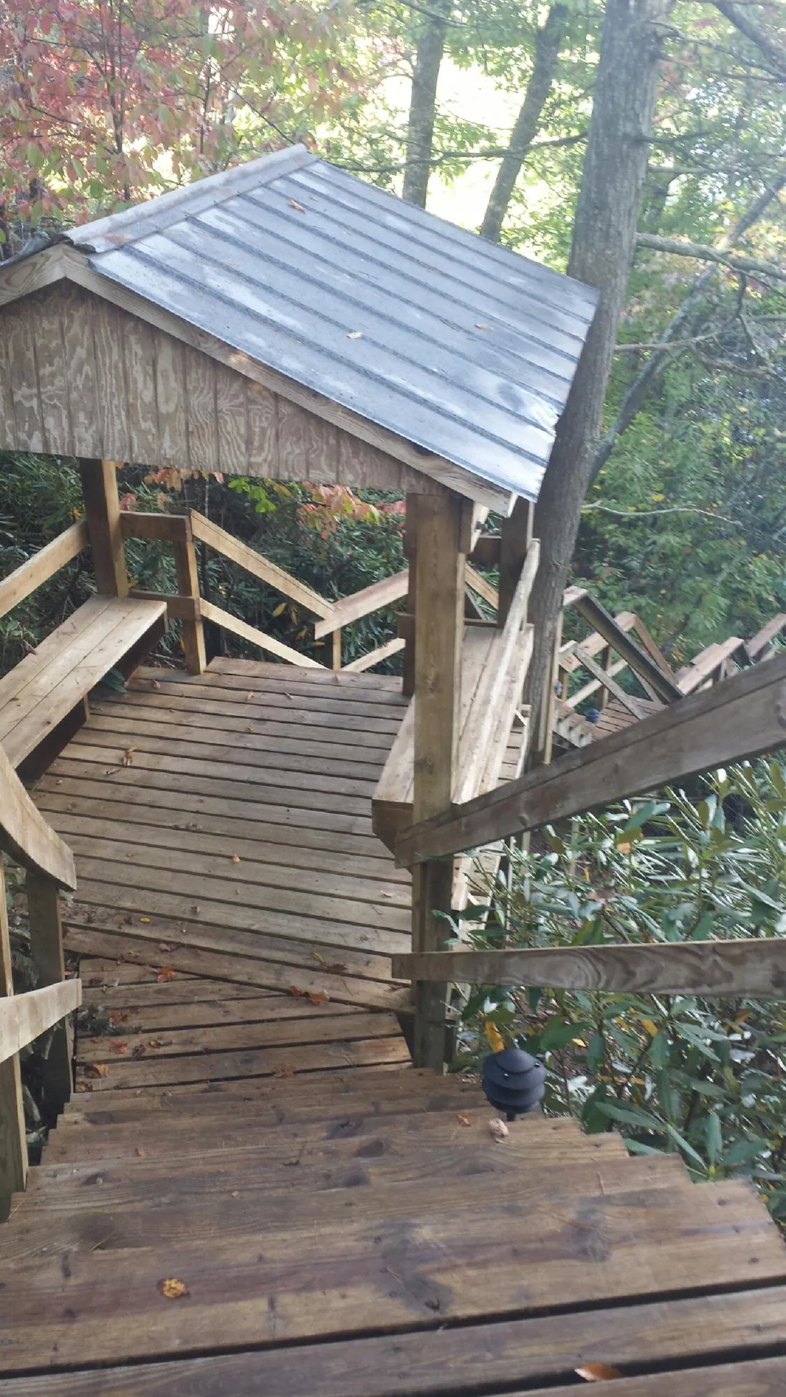 Metal roofed shelter over wooden steps on a wooded walkway — Skylight Repair & Installation work by our crew in Sebeka